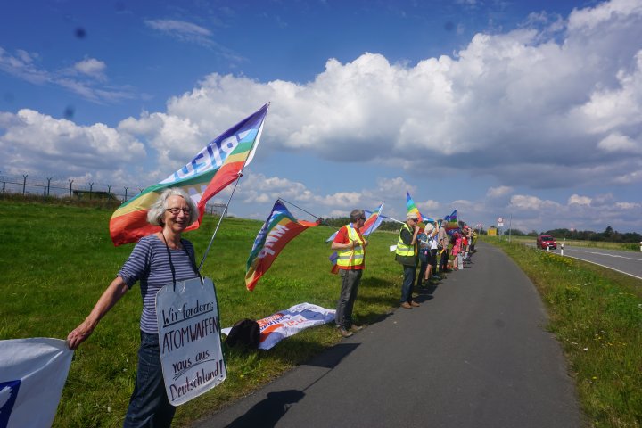 Menschen und Fahnen bei einer Menschenkette am Atomwaffenstützpunkt in Büchel